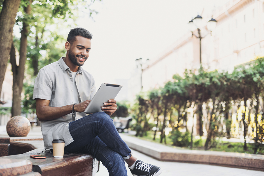 Client Center - Smiling Young Man Using Tablet Outside in a City in Missouri